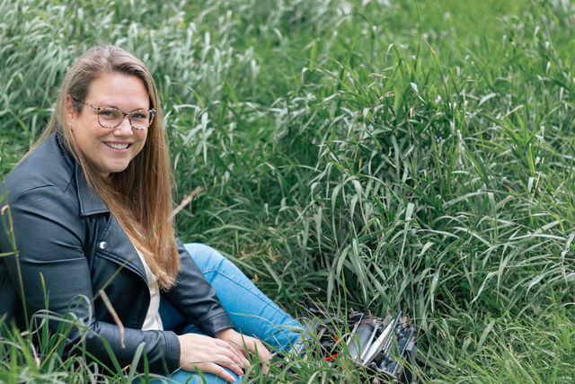 Kirsten zit in het gras met een ouderwetse typemachine.